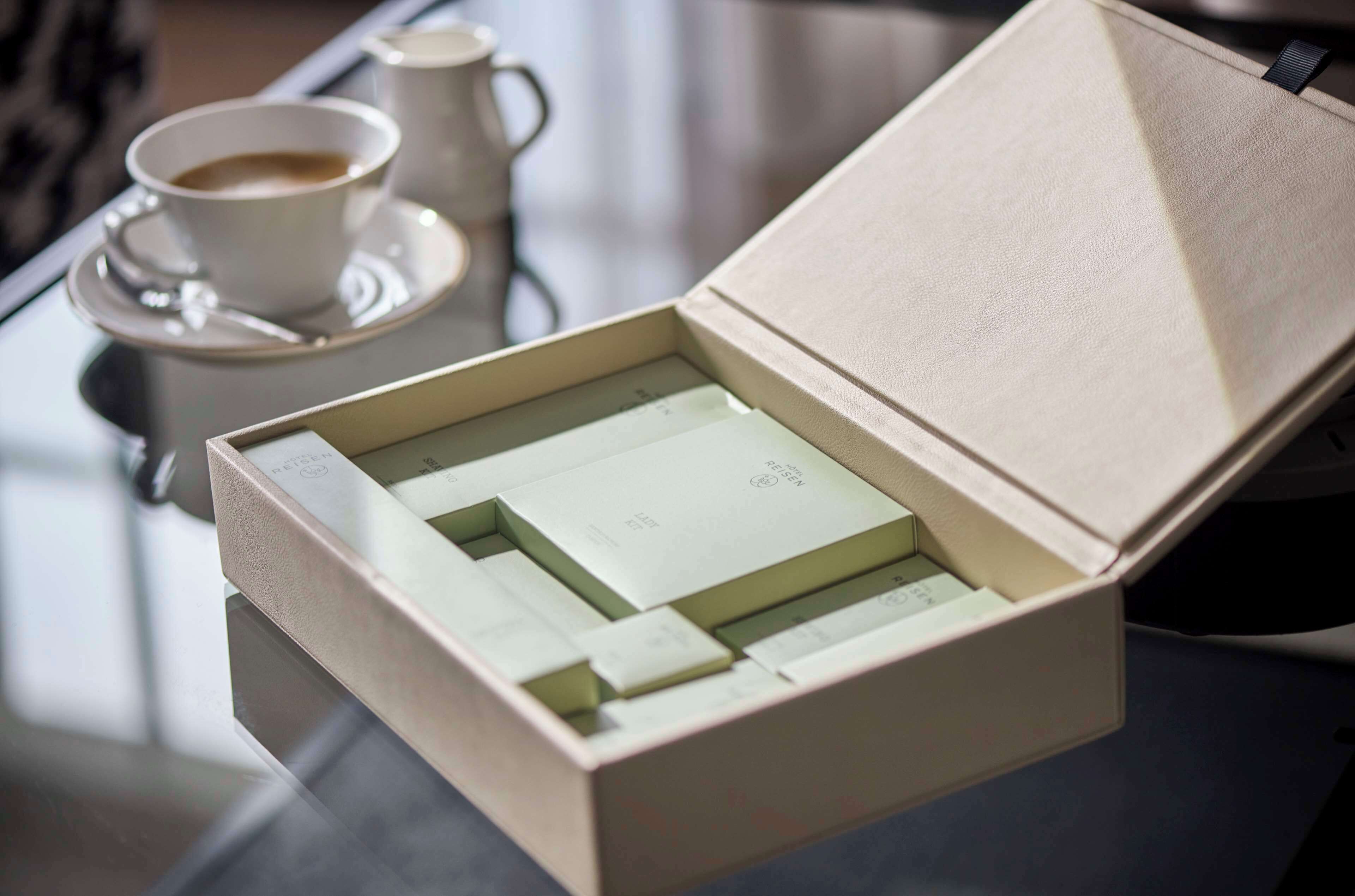 Una caja con una tarjeta en su interior, colocada sobre una mesa junto a una taza de café.