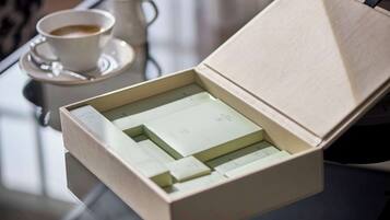 Una caja con una tarjeta en su interior, colocada sobre una mesa junto a una taza de café.