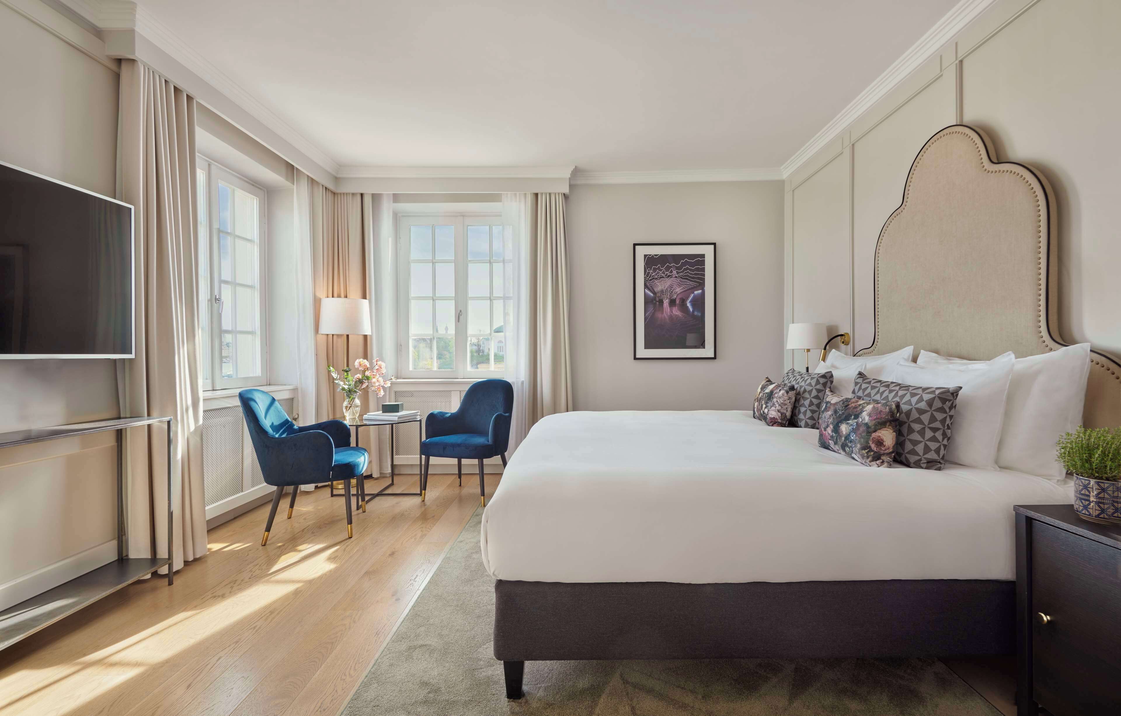 Een hotelkamer met een groot bed, een televisie, een bureau met stoel, en een raam met gordijnen.