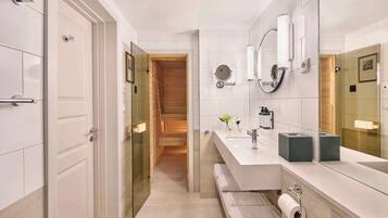 A modern bathroom with a glass shower enclosure, a large mirror, and a white vanity.