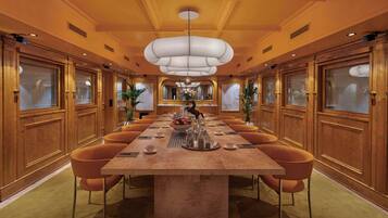 A spacious conference room with a long table, comfortable seating, and a modern chandelier.