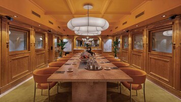 A spacious conference room with a long table, comfortable seating, and a modern chandelier.
