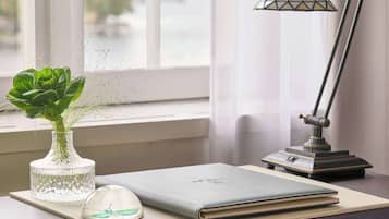 Un bureau avec un ordinateur portable, un vase avec une plante, une souris et une lampe de bureau.