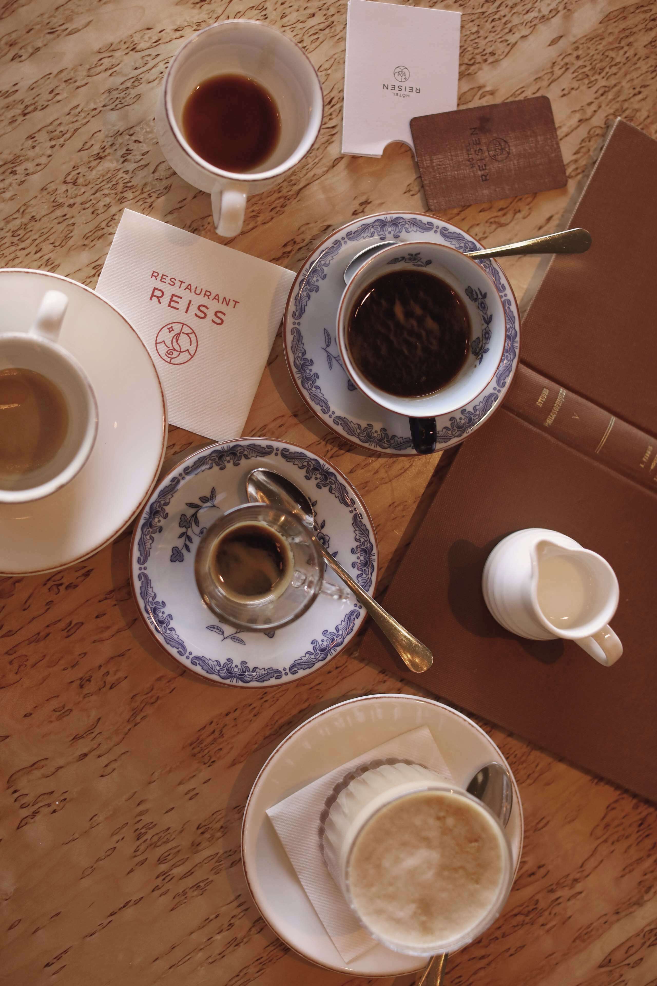 Una taula amb un menú, un quadern i diverses tasses de cafè.