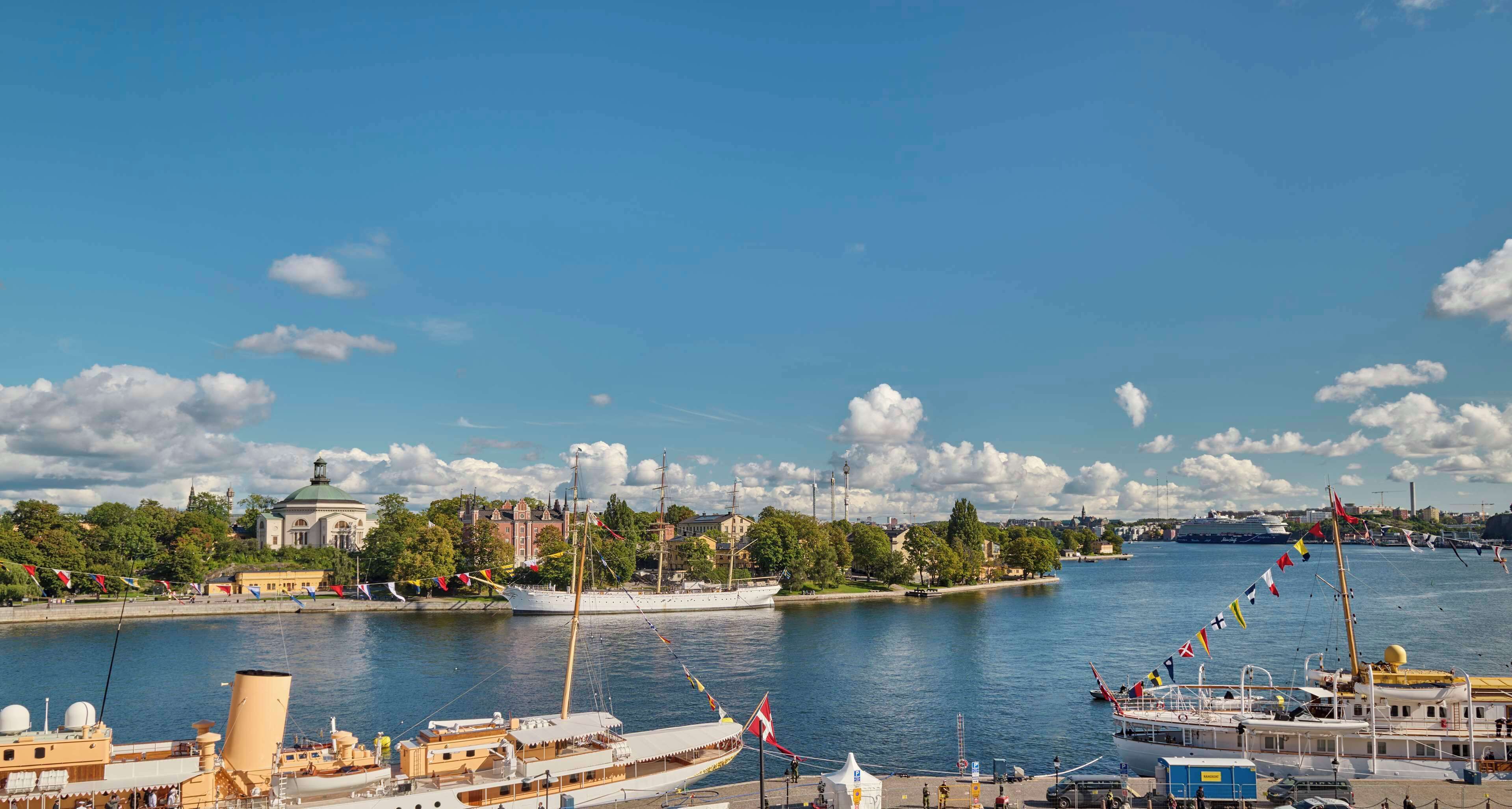 A harbor with a large sailing ship, a white building with a dome, and a river.