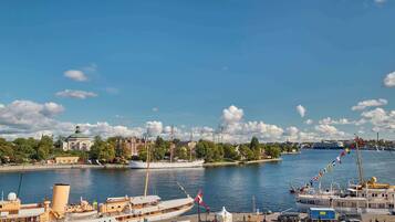 A harbor with a large sailing ship, a white building with a dome, and a river.