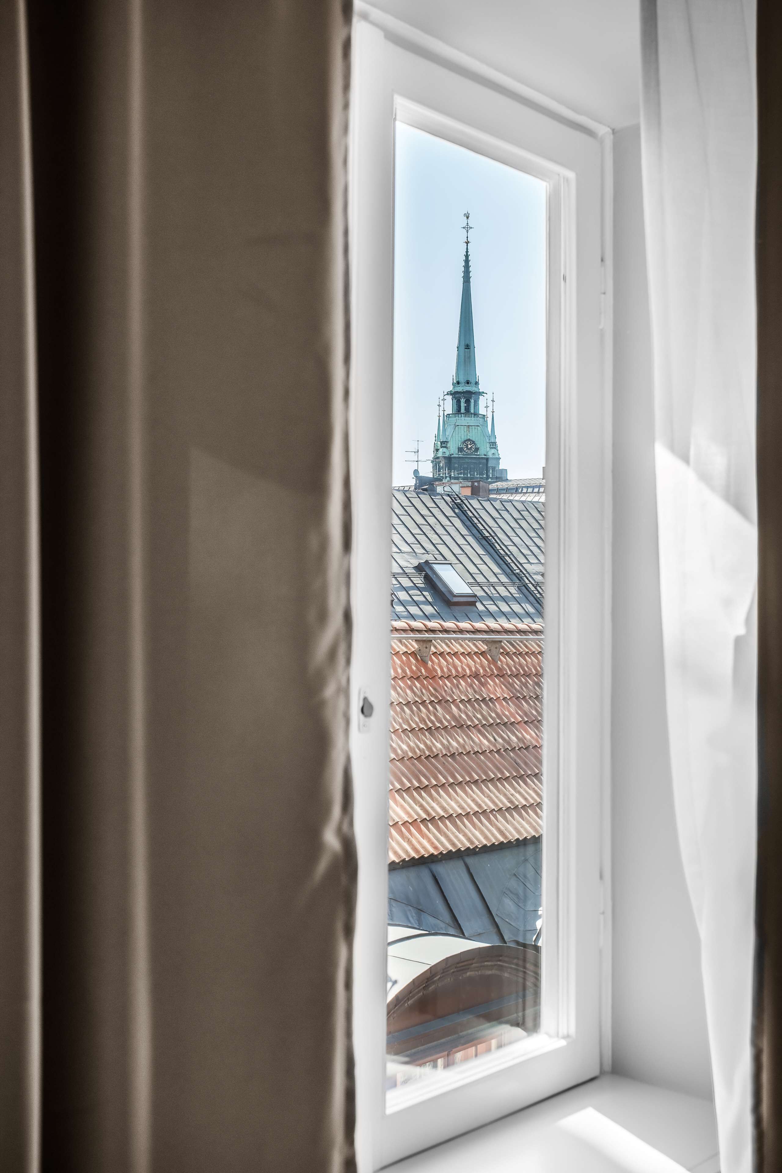 A window with a view of a building with a spire.