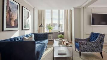 Una sala de estar moderna con un sofá azul, un sillón estampado de leopardo, una mesa de centro y un ventanal con cortinas.