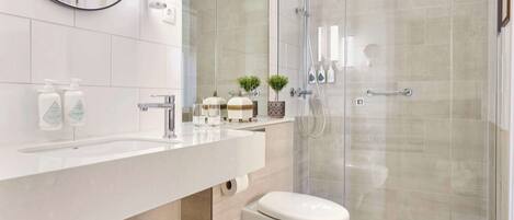 Une salle de bain moderne avec une douche à parois de verre, un lavabo blanc et des toilettes.