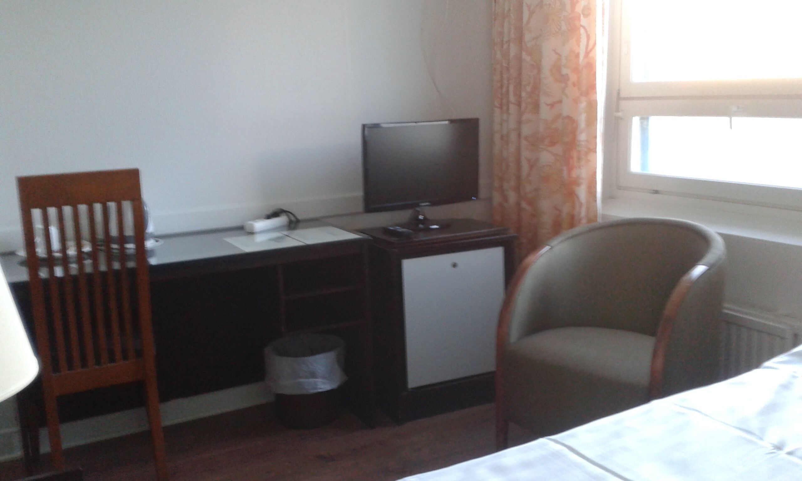 Una habitación de hotel con escritorio, televisor, silla y cama.