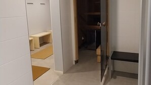 A hallway with a bench, a door leading to another room, and a tiled floor. - Kauppahotelli (Lahti)