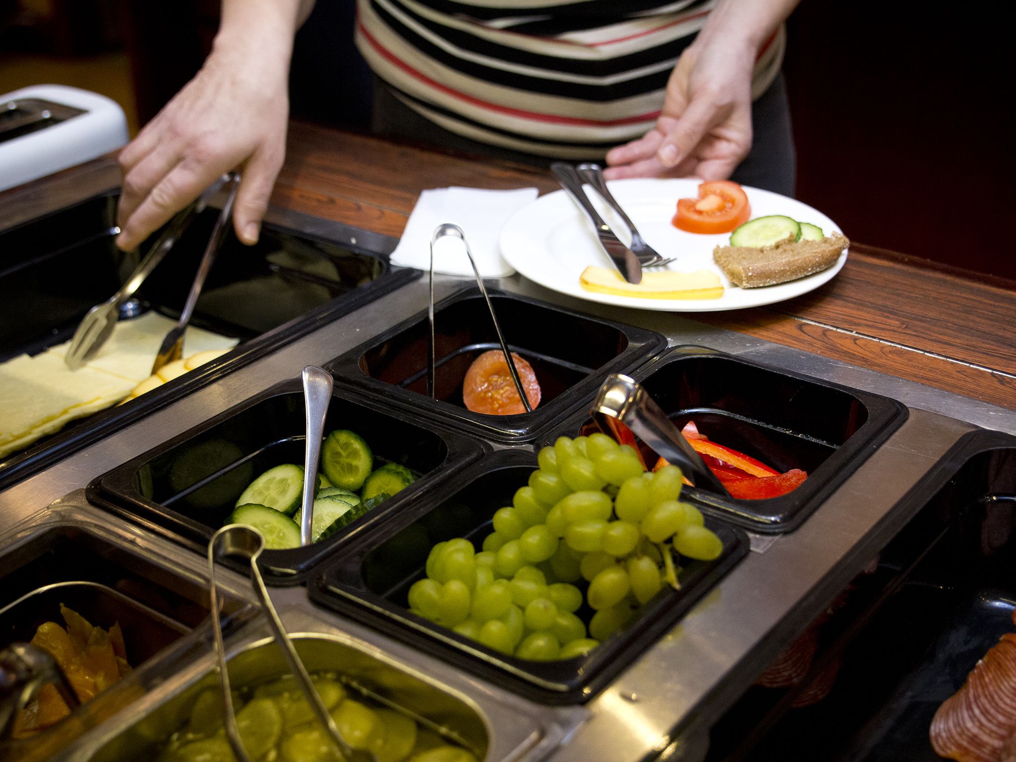 Un buffet proposant une variété de plats, notamment des raisins, des concombres et des tomates.