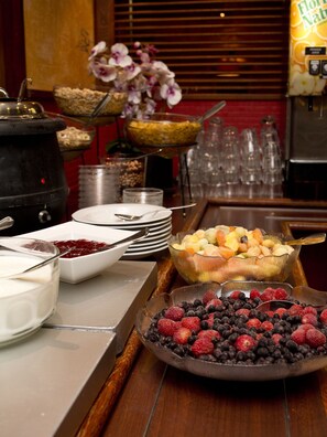 Un buffet con diversi cibi, tra cui frutta e una ciotola di yogurt.