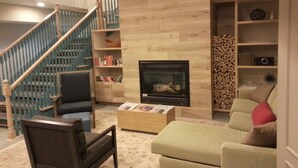 A living room with a fireplace, a staircase, and a bookshelf. - Country Inn & Suites by Radisson, Columbus Airport, OH (Columbus)