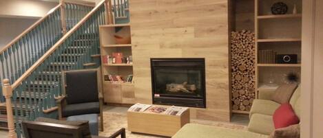 Una sala de estar con chimenea, una escalera y una estantería.