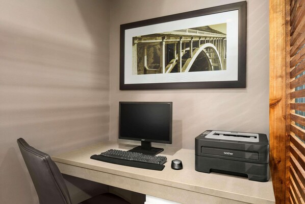 A desk with a monitor, keyboard, and Brother printer.