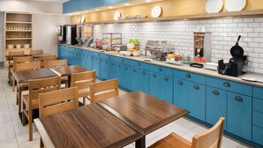A modern breakfast area with blue cabinets, wooden tables, and a variety of breakfast items. - Country Inn & Suites by Radisson, Columbus Airport, OH (Columbus)