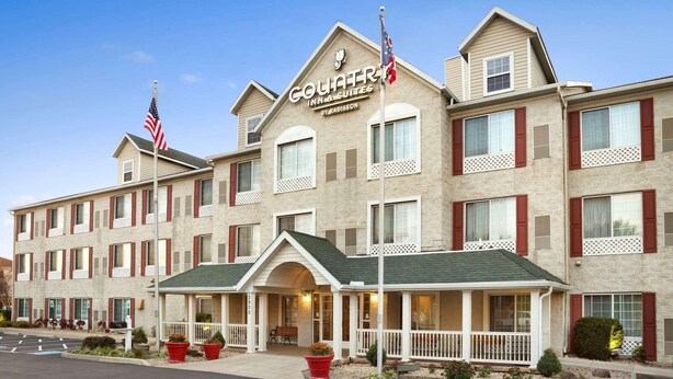 A hotel with a central entrance, multiple windows, and a sign indicating it is a Courtyard Inn & Suites. - Country Inn & Suites by Radisson, Columbus Airport, OH (Columbus)