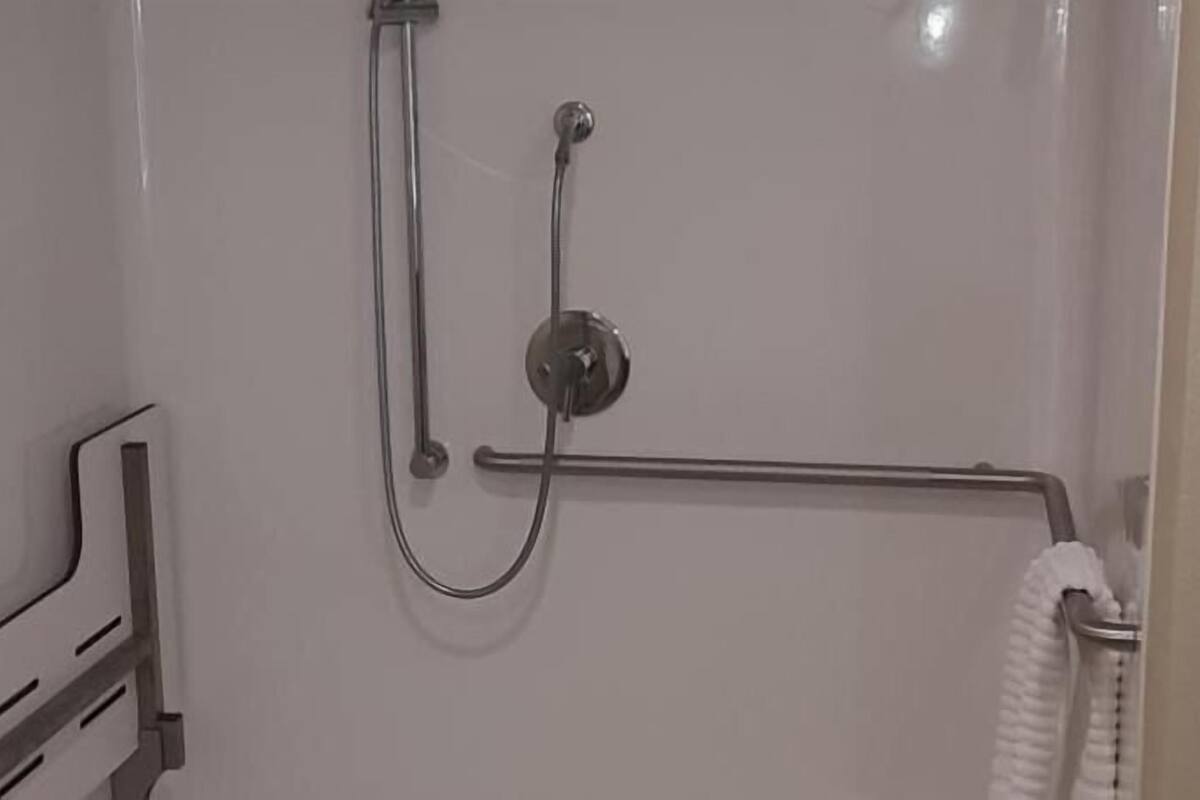 Un espace douche équipé d’une barre d’appui, d’un porte-serviettes et d’un robinet fixé au mur.