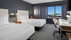 A hotel room with two beds, a desk, and a chair. There is a large window with curtains, and a view of the cityscape. - Courtyard by Marriott Chattanooga Downtown (Chattanooga)