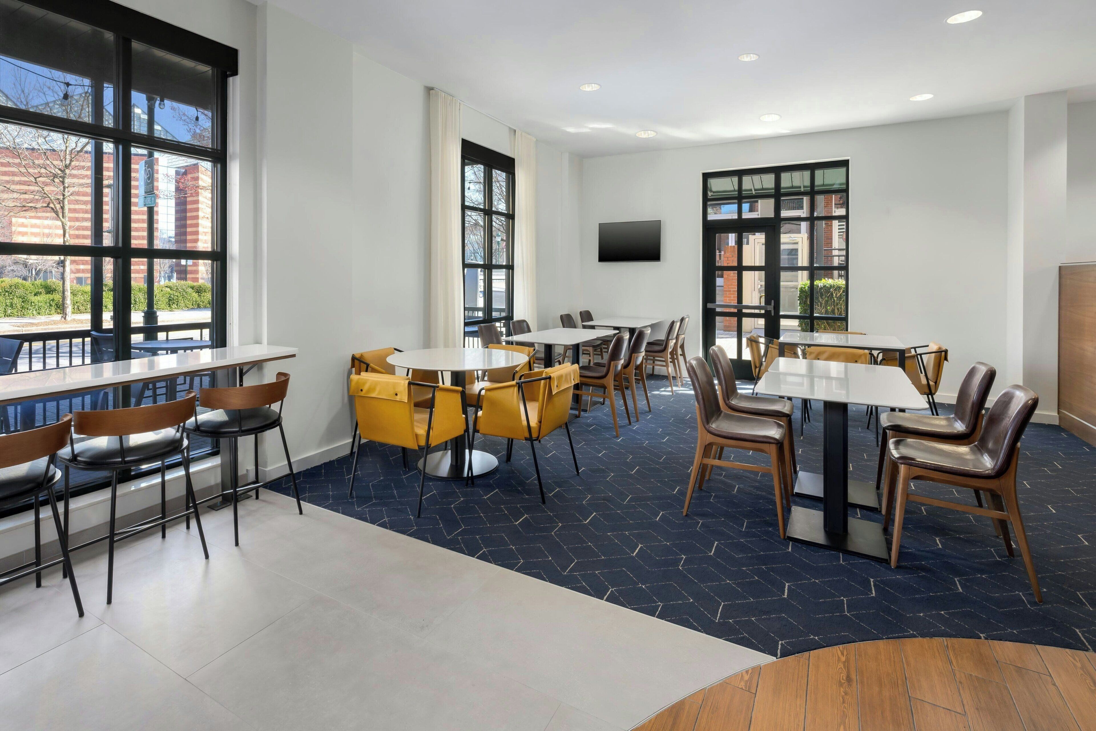 A modern conference room with large windows, multiple tables, and chairs.