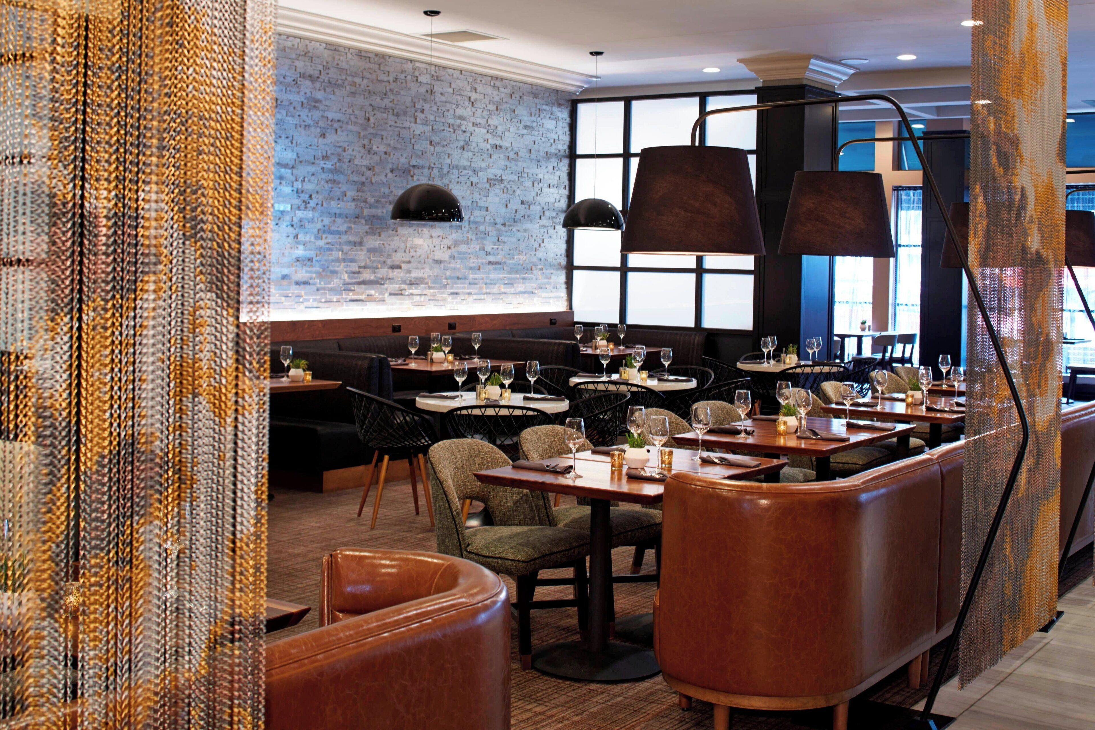 A restaurant with brick walls, leather booths, and pendant lighting.