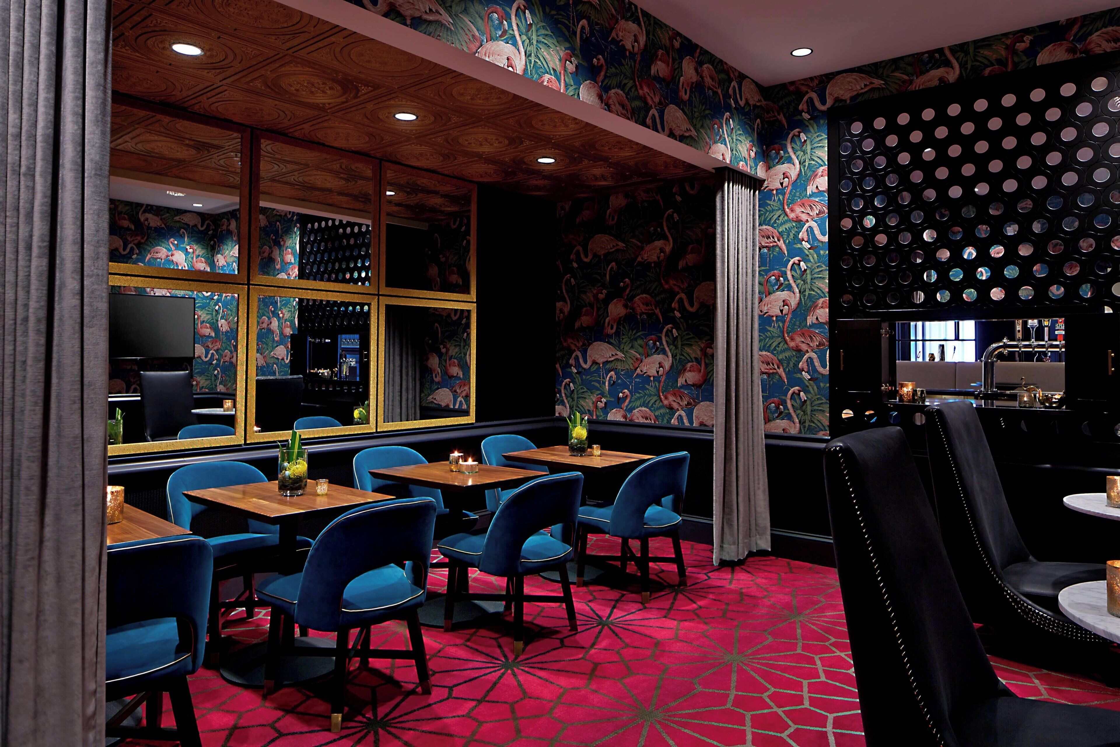 Un restaurante con sillas azules, mesas de madera y una alfombra roja estampada.