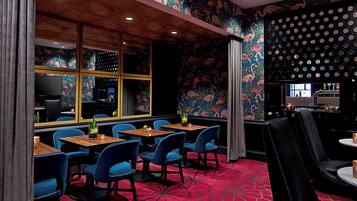 Un restaurante con sillas azules, mesas de madera y una alfombra roja estampada.