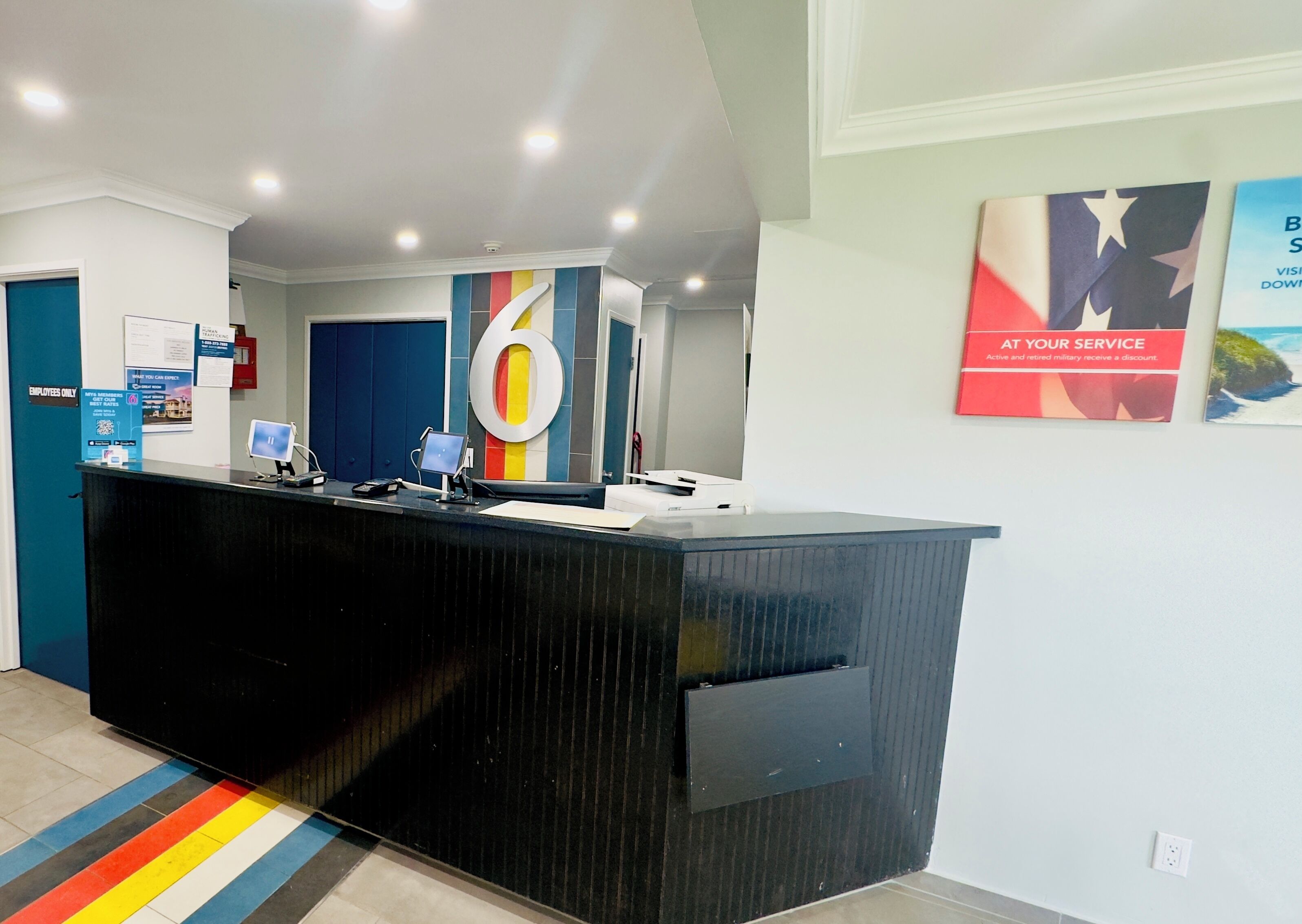 A reception desk with a large number 6 sign, a blue door, and a colorful striped rug.