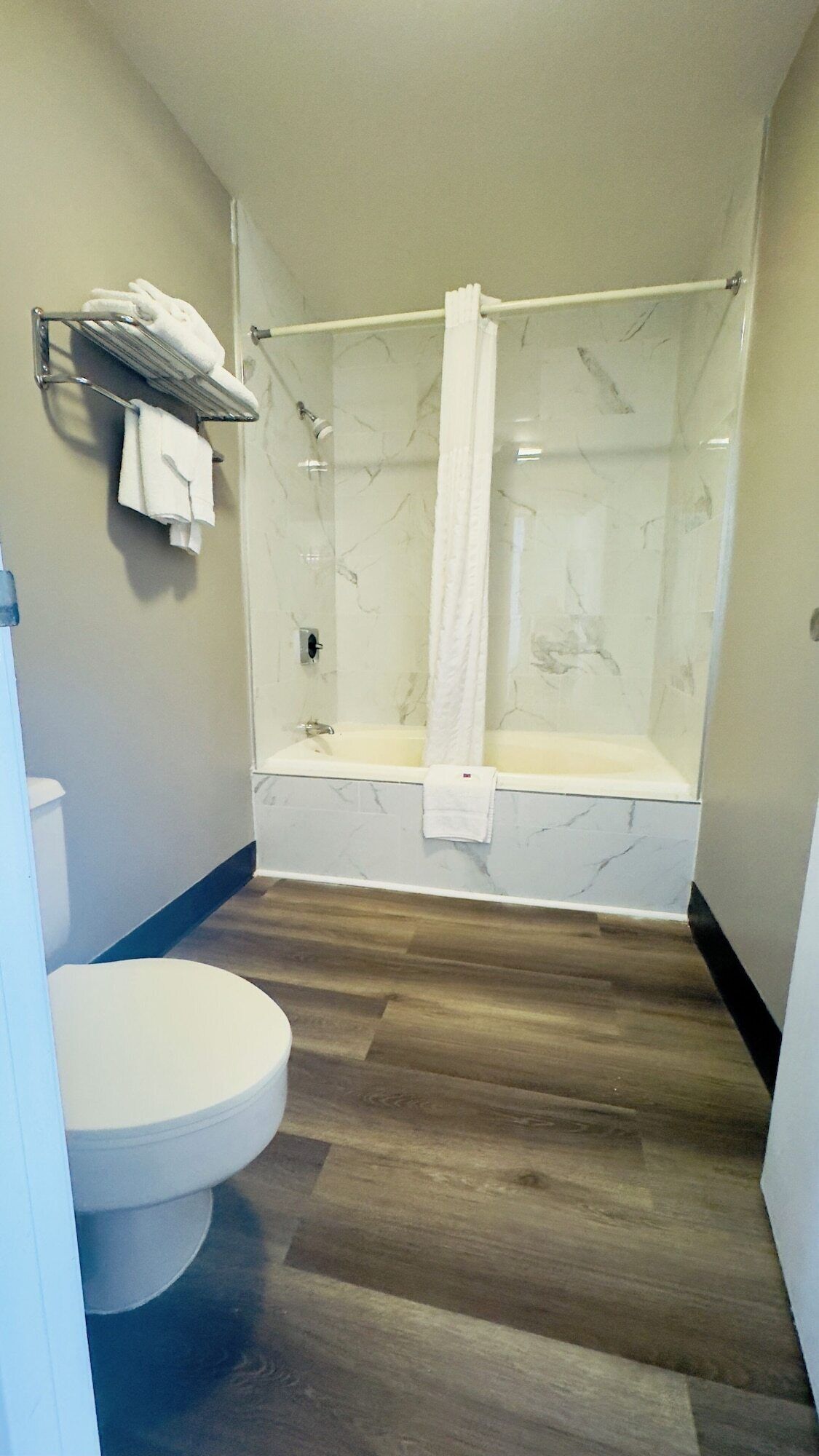A bathroom with a shower, toilet, and a towel rack.