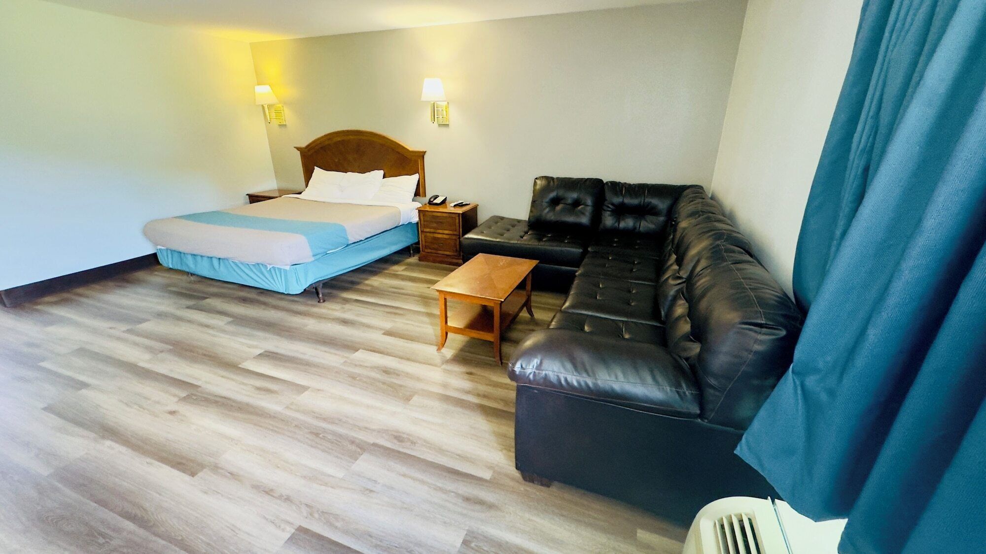 Una habitación de hotel con cama, sofá, una mesita y dos lámparas de pared.