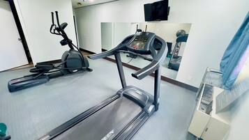 Ein Fitnessraum mit Laufbändern, einem Ergometer und einer Spiegelwand.