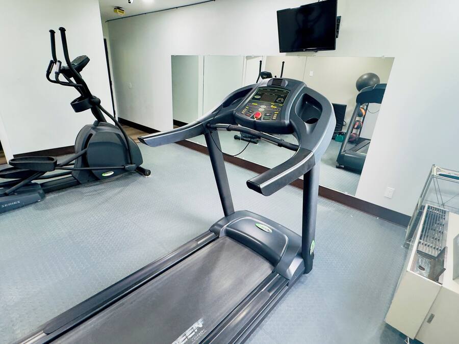 Ein Fitnessraum mit Laufbändern, einem Ergometer und einer Spiegelwand.