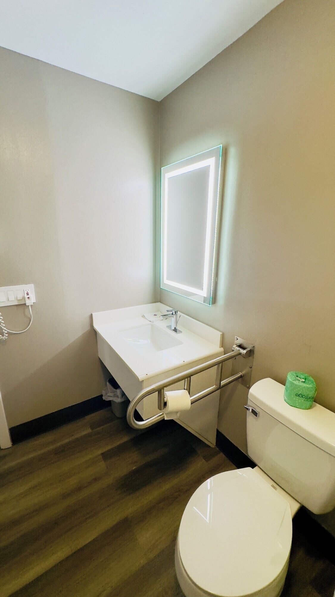 Et badeværelse med hvid vask, spejl og toilet.