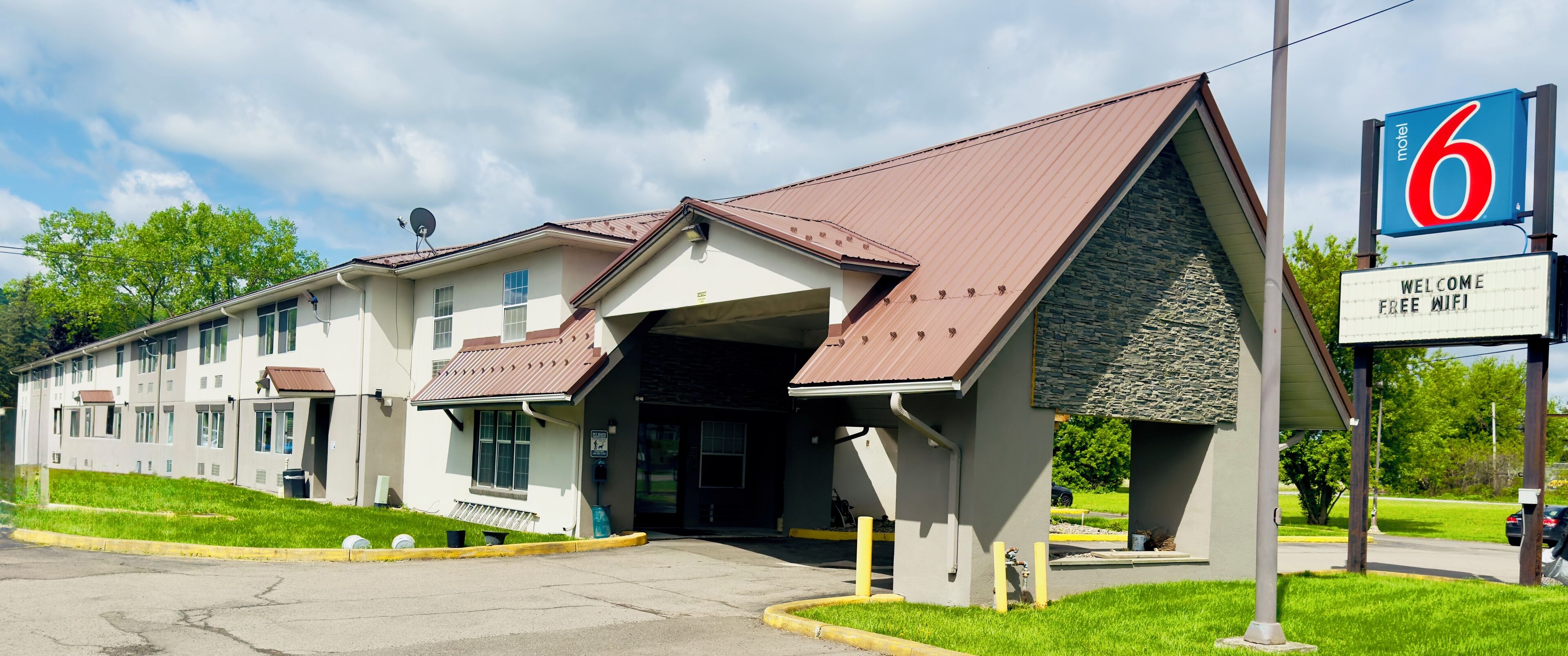 A motel with a sign indicating free WiFi, a stone facade, and a parking lot.