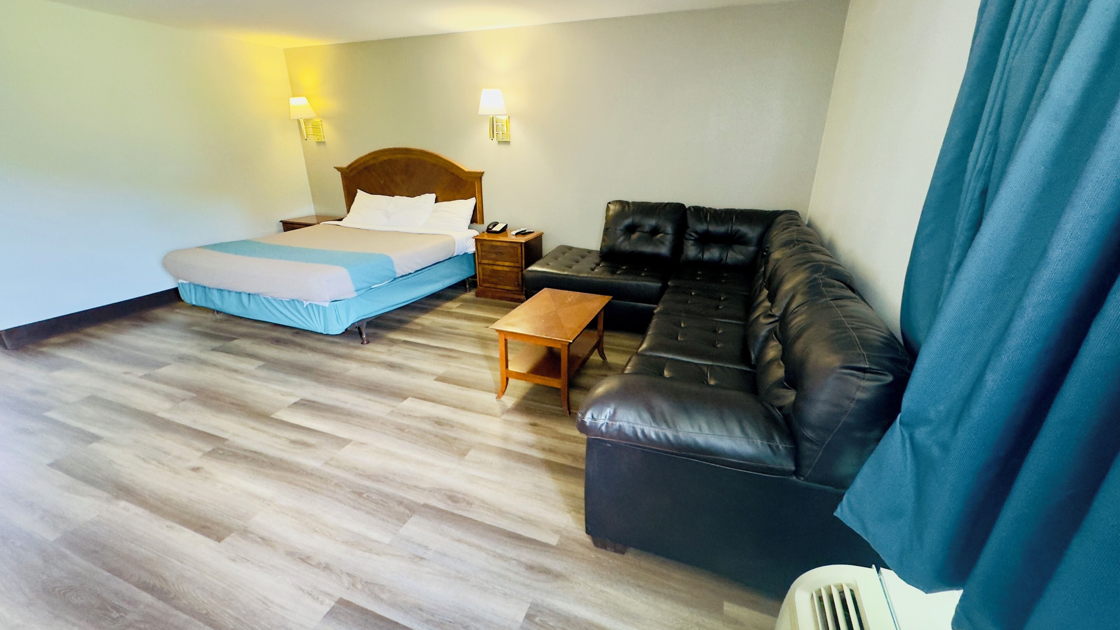 Una habitación de hotel con cama, sofá, mesita de noche y mesa de madera.