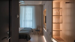 Un dormitorio moderno con una cama, una silla y un armario de madera con estantes.