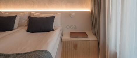 A modern bedroom with a bed, bedside table, and a nightstand.