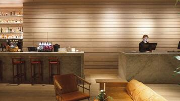 A bar area with wooden paneling, a bar counter, stools, and a seating area with a sofa and a table.