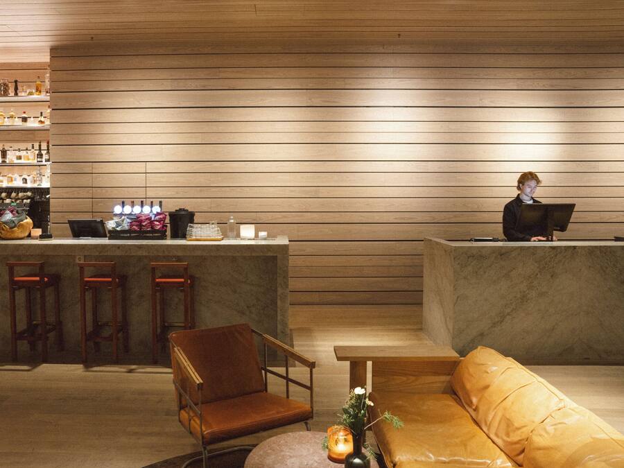 A bar area with wooden paneling, a bar counter, stools, and a seating area with a sofa and a table.