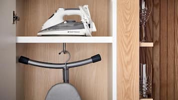 A compact storage unit with a built-in ironing board and a shelf for decorative items.