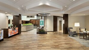 A spacious lobby with a wooden floor, a reception desk, a sign with an 'E', and a modern ceiling design. - Embassy Suites by Hilton Atlanta Alpharetta (Alpharetta)