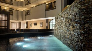 A multi-level indoor pool area with stone walls and multiple balconies. - Embassy Suites by Hilton Atlanta Alpharetta (Alpharetta)