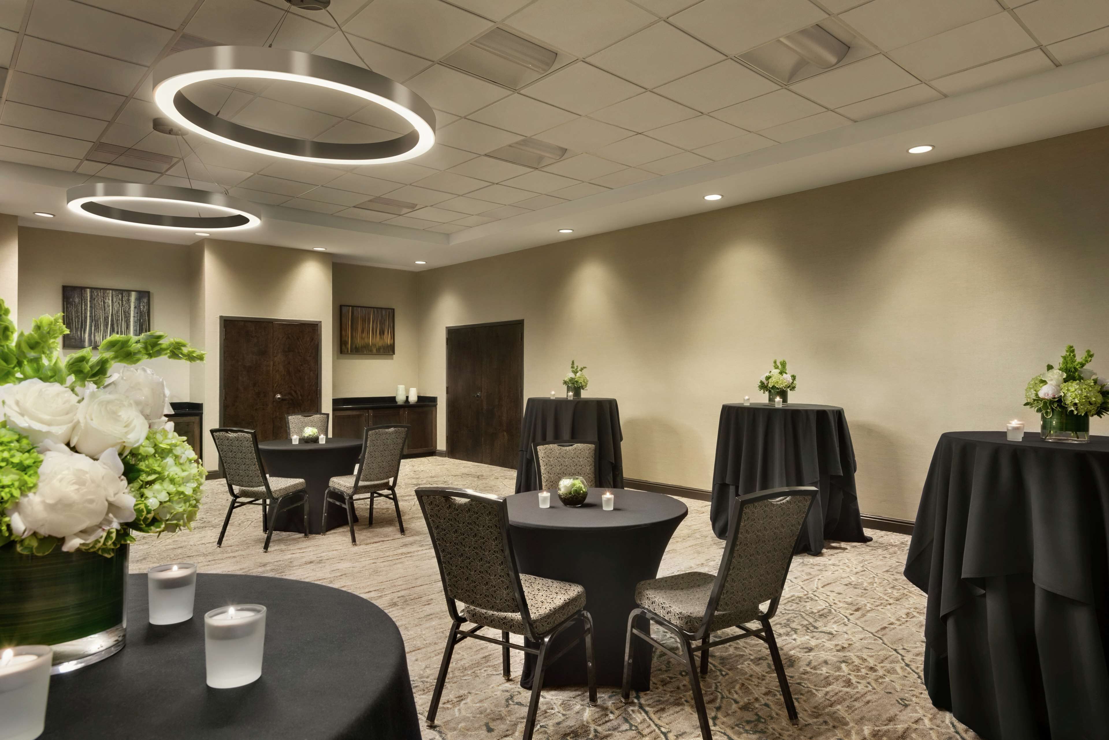 A conference room with round tables, chairs, and floral centerpieces.