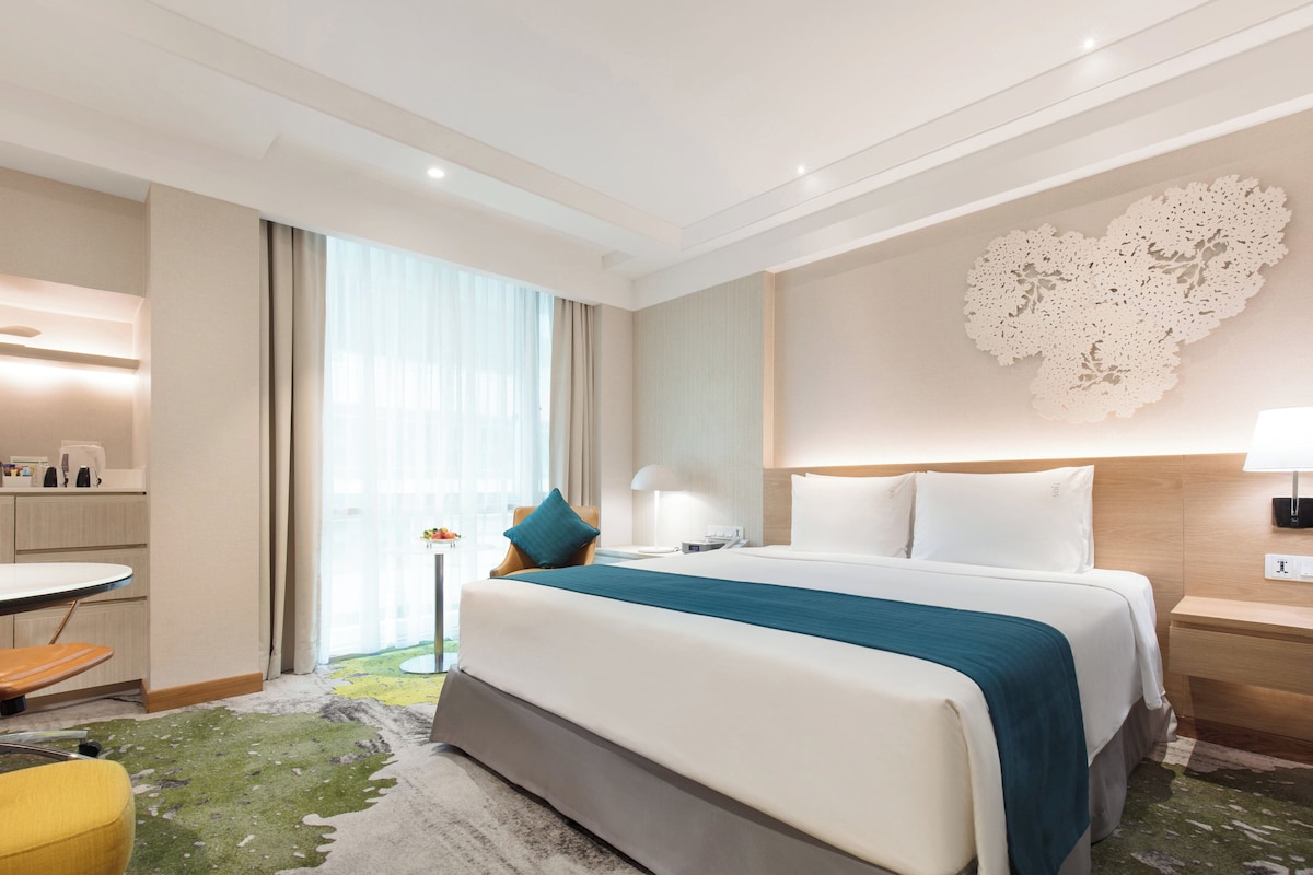 Hotellihuone, jossa on sänky, yöpöydät, työpöytä ja tuoli.