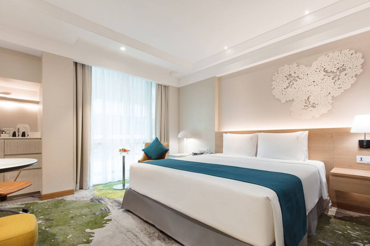 Camera d'albergo con un letto grande, una scrivania, una sedia e vista sull'esterno.