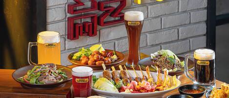 Un bar con una variedad de comida y bebidas, incluyendo hamburguesas, papas fritas y cerveza.