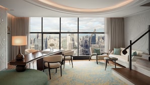 A modern hotel room with a city view, a dining area, and a staircase.