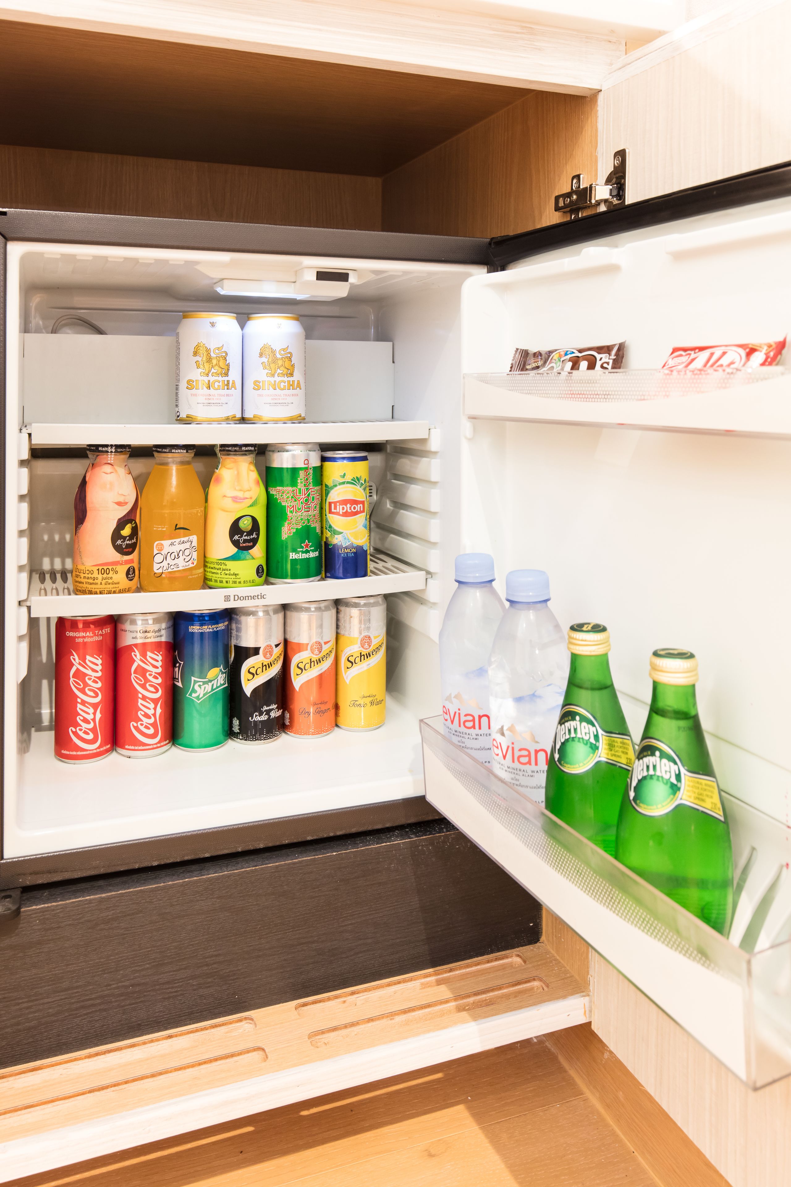 An open refrigerator stocked with various beverages including sodas, juices, and beers.