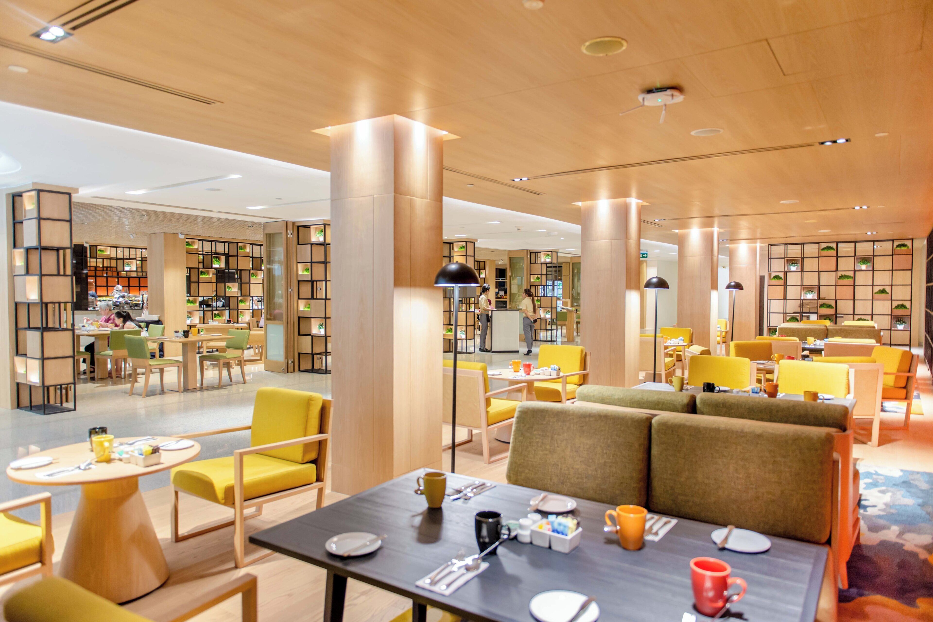 A modern interior with a dining area, seating arrangements, and a reception desk.